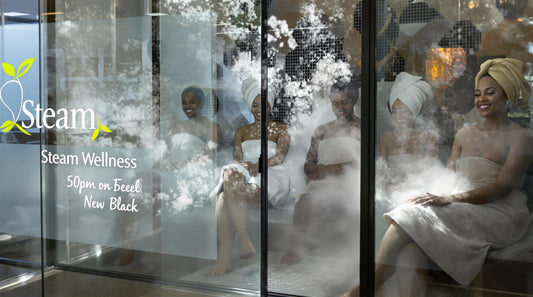 Group of adults relaxing in a modern steam room, wellness center signage visible
